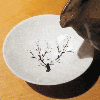 Mira cómo este sake dibuja un árbol de cerezo en una taza